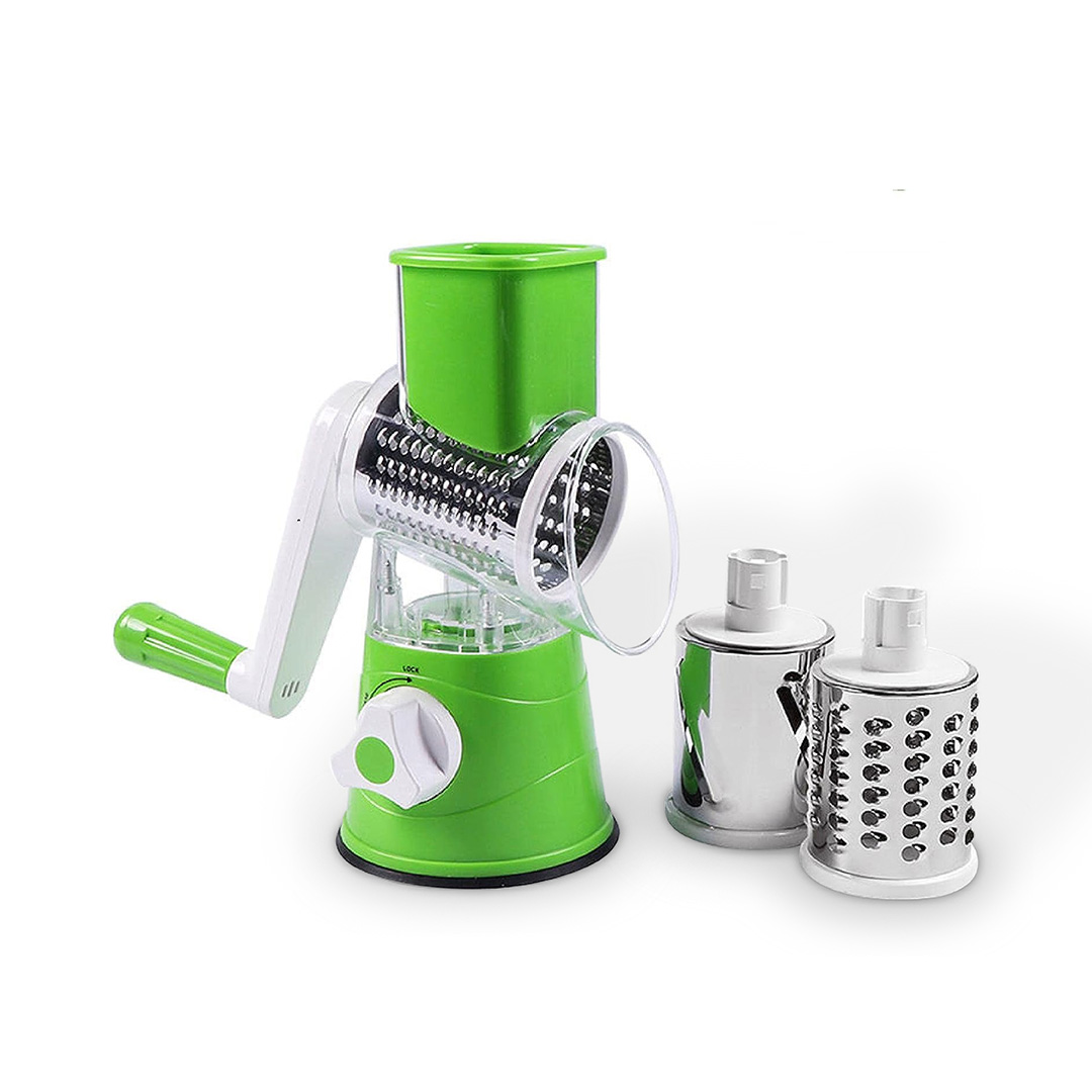 rallador de verduras rotativo verde con tambores de acero inoxidable cortando pepinos y zanahorias en una cocina moderna.