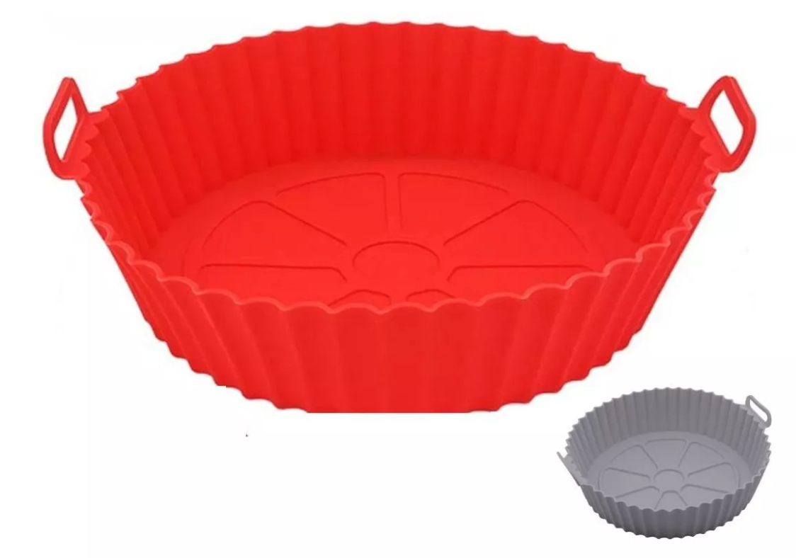 canasta de silicona roja para air fryer con diseño circular y ranuras para circulación de aire sobre una encimera de cocina.